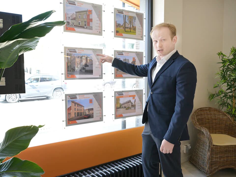 Un agente inmobiliario muestra los anuncios expuestos en el escaparate.